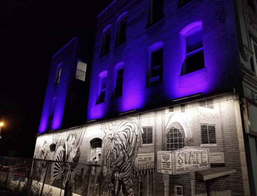 Purple uplighting on a Main Street building above a lit theater mural